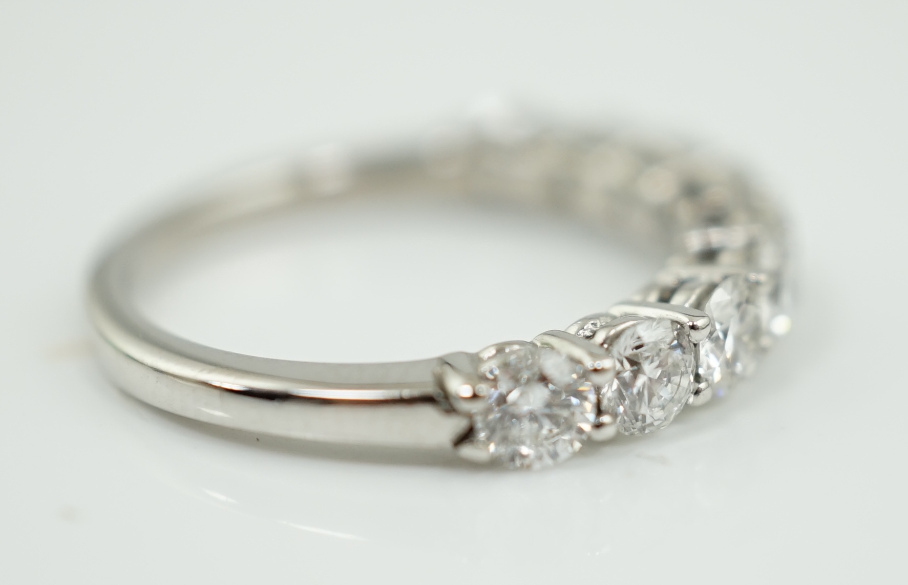 A white gold and nine stone set round brilliant cut diamond set half hoop ring
